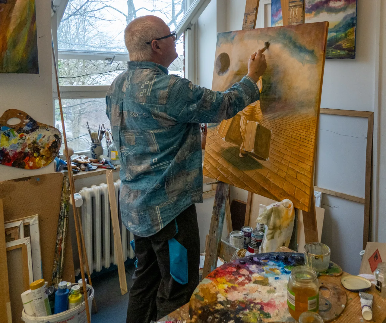 Kowalke arbeitet im Atelier vor der Staffelei, neben ihm liegen Palette und Pinsel.