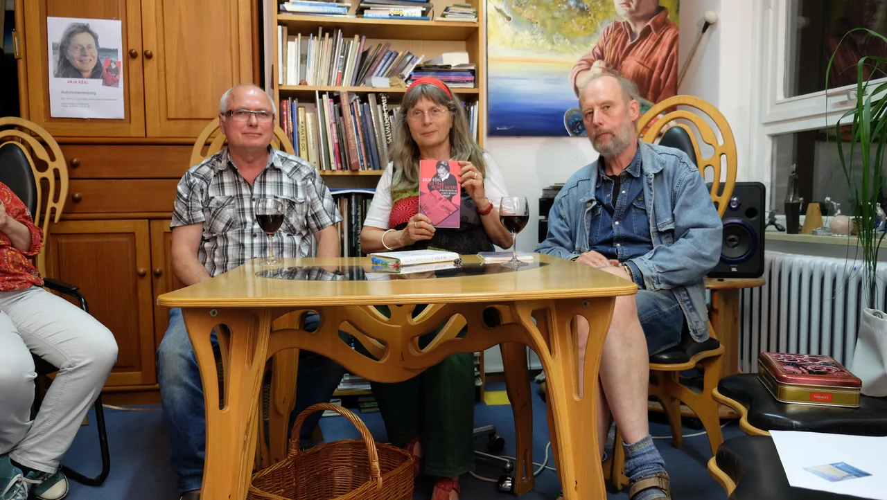 Drei Personen sitzen an einem Tisch; in der Mitte wird das Buch „Die Frau meines Vaters“ von Anja Röhl gezeigt.