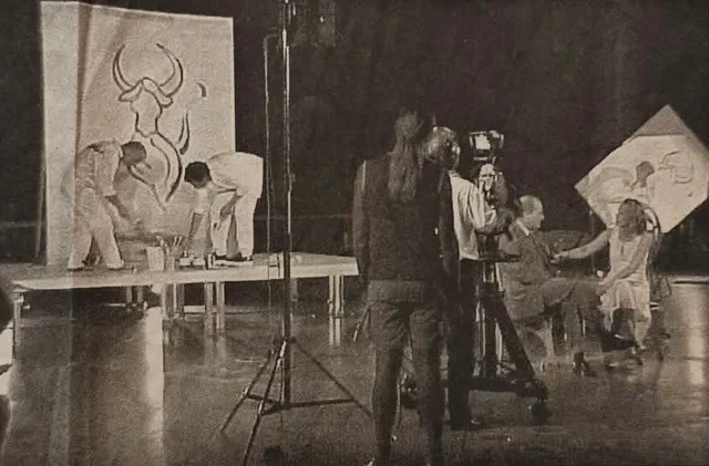 Zeitungsfoto von Malern und Fernsehkameras bei einer Aktion auf einer Bühne