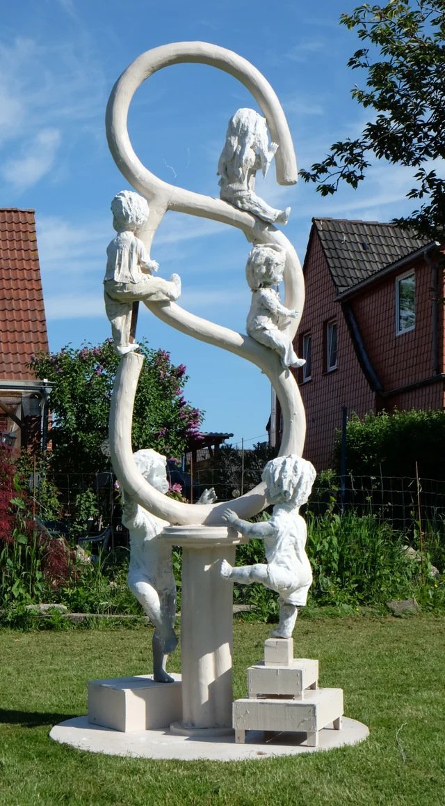 Weißes Modell mit Kinderfiguren an geschwungenen Ringen auf einer runden Grundplatte