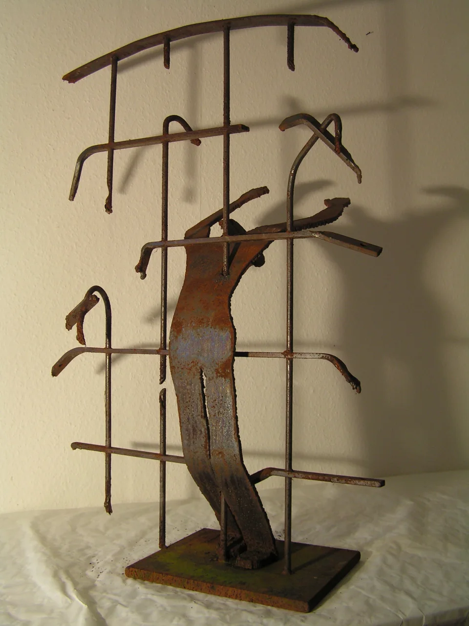 Metallene menschliche Figur vor einem rechteckigen Gitter - Eckhard Kowalke